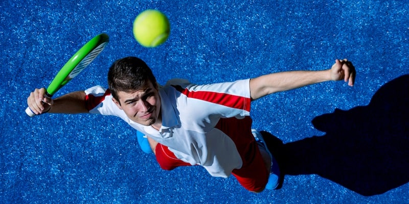 A paddle tennis player sees the ball go down and prepares to shoot.