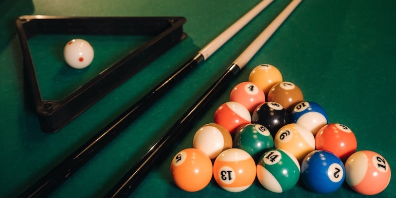 Cues and balls are displayed on the pool table.