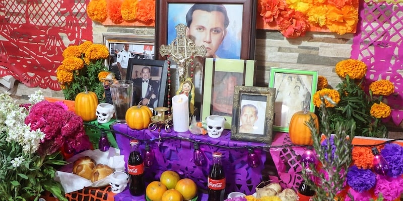 An altar of the dead includes photographs of the deceased and different offerings.