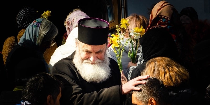 An Orthodox priest is surrounded by worshipers during a pilgrimage.