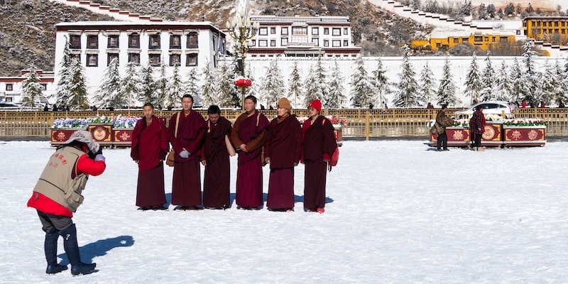 Tibetan monks pose in front of the Palace