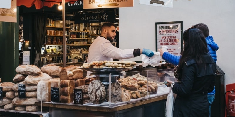 A woman buys consumer goods at a bread stall.