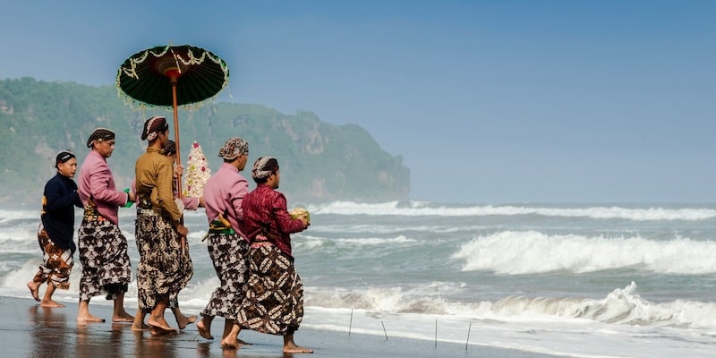 A group of people bring offerings to the sea.