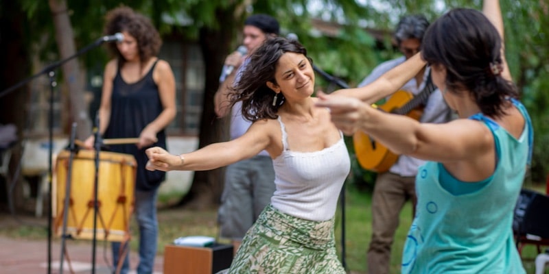 The women dance while a band plays folk music.