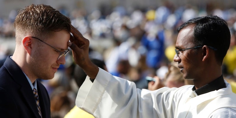 A priest gives a blessing to a faithful in the Vatican.